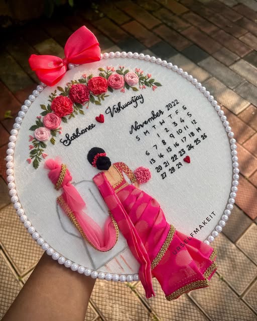 Traditional wedding hoop: an embroidered bride in a pink saree beside a stitched calendar